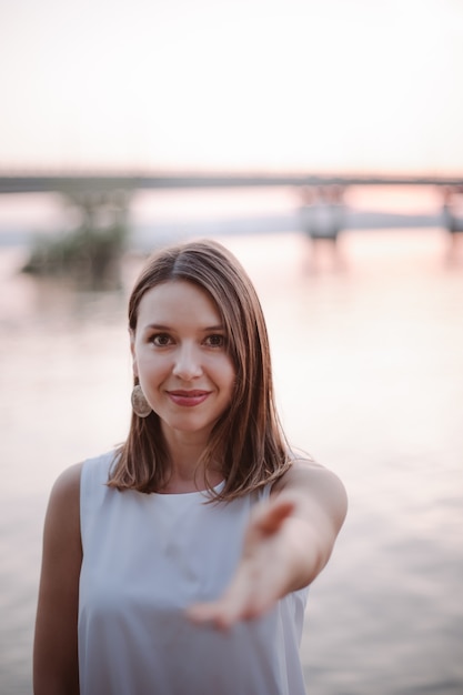 Une femme caucasienne souriante et souriante tend la main vers la caméra et propose d'aller à un rendez-vous ou à...