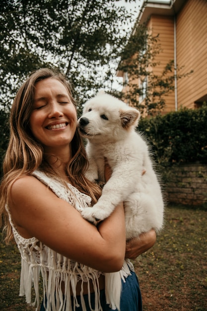 Photo femme caucasienne souriante tenant le chiot samoyède dans ses bras. concept d'animaux et de personnes. concept d'animaux mignons.