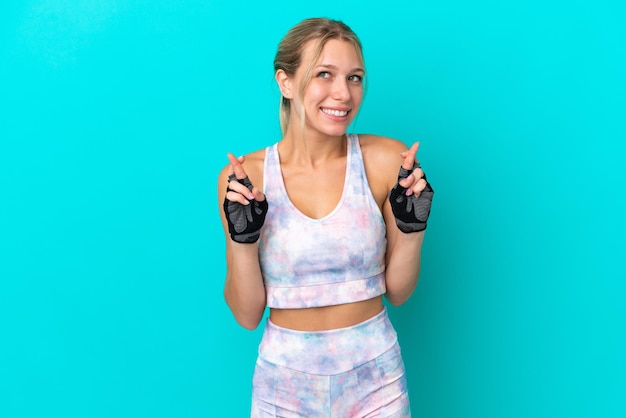 Femme caucasienne sport isolée sur fond bleu avec croisement de doigts