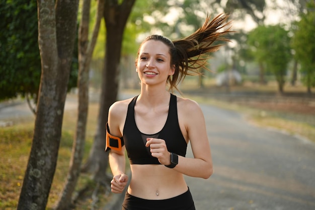 Femme caucasienne sportive active portant des vêtements de sport faisant du jogging sur la route dans le parc d'été au lever du soleil Concept de mode de vie sain et actif