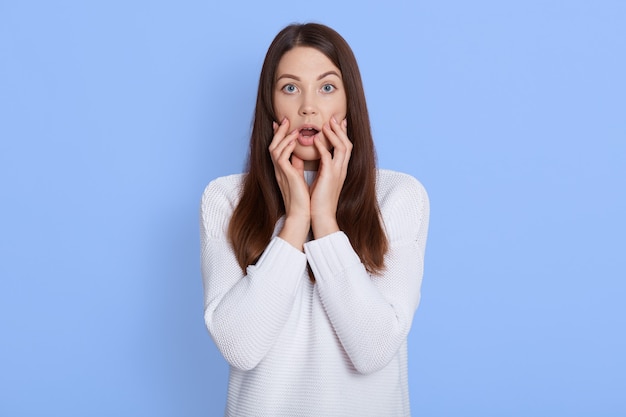 Femme caucasienne stupéfaite regarde la caméra avec de grands yeux et garde la bouche ouverte