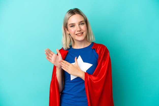 Femme caucasienne de super héros isolée sur fond bleu applaudissant après présentation lors d'une conférence