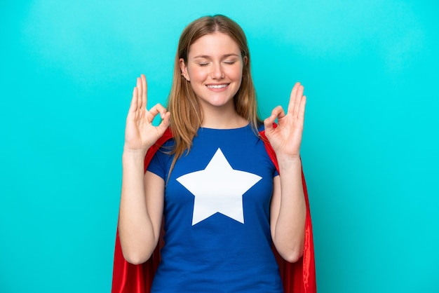 Femme caucasienne de super héros isolée sur fond bleu dans une pose zen