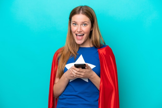 Femme caucasienne de super héros isolée sur fond bleu surpris et envoyant un message