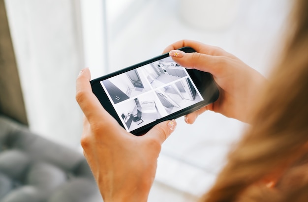 Femme caucasienne surveillant les caméras de sécurité sur smartphone à l'intérieur, gros plan.