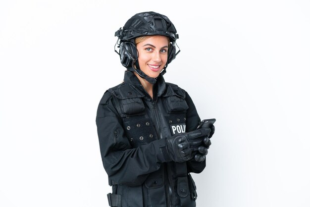 Femme caucasienne SWAT isolée sur fond blanc envoyant un message avec le mobile