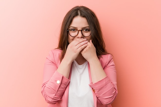 Femme caucasienne de taille plus entreprise jeune rire en riant de quelque chose, couvrant la bouche avec les mains.