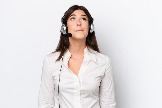 Femme caucasienne de télévendeur travaillant avec un casque isolé sur fond blanc et levant les yeux