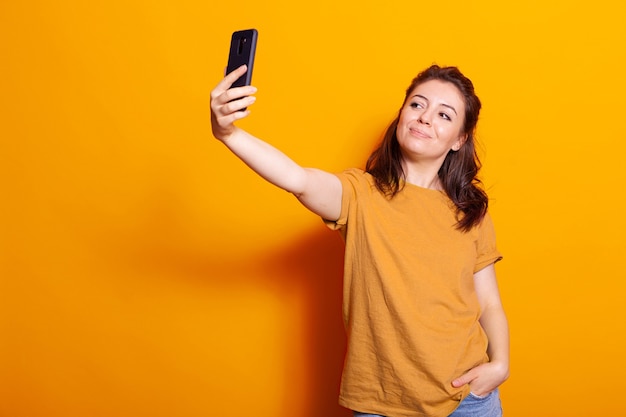 Femme caucasienne tenant un smartphone pour prendre des selfies