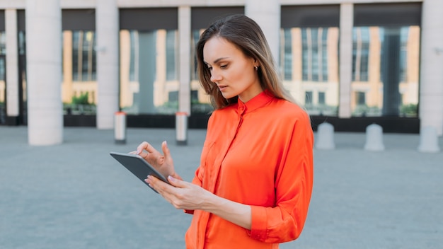 Femme caucasienne tenant une tablette dans ses mains et tapant un message.