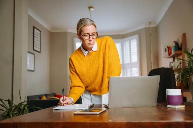 Femme caucasienne travaillant à domicile écrivant sur un document