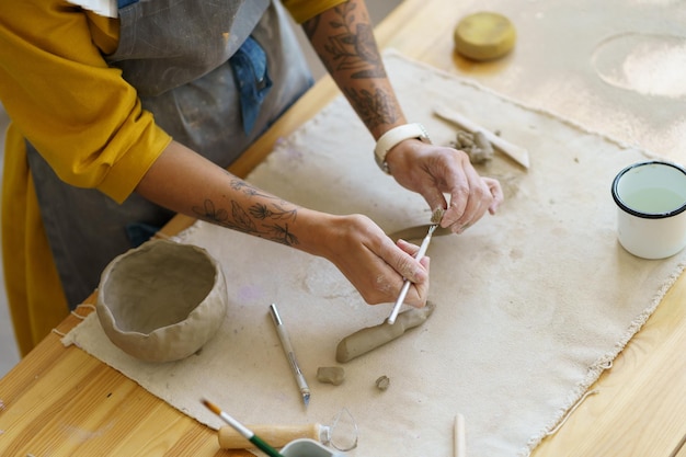 Femme céramiste faire une tasse de poterie en studio maître de poterie fille créative avec une tasse de pot de mise en forme de tatouage