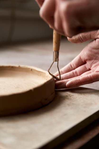 Femme céramiste travaillant dans un studio de poterie. Mains De Céramiste Sale D'argile. Processus de création de poterie. Maître céramiste travaille dans son atelier