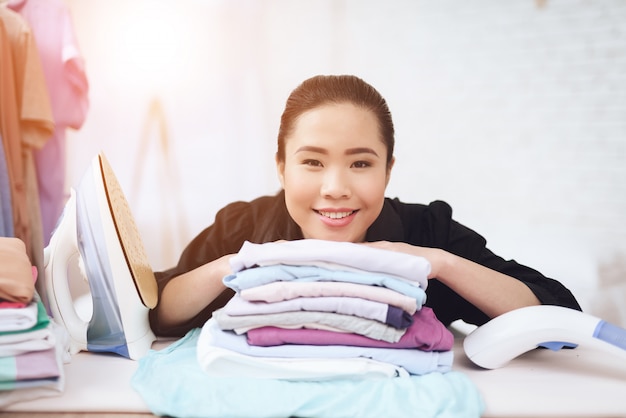 Femme de chambre asiatique souriante avec des vêtements pliés.