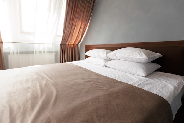 Femme de chambre avec des oreillers et des draps blancs propres dans la salle de beauté.