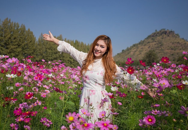 femme avec champ de fleurs cosmos