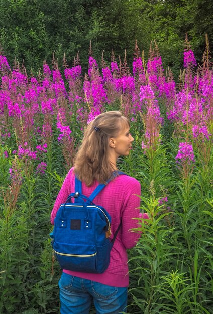 Femme sur un champ de saule en fleurs. Concept de voyage avec un sac à dos léger.