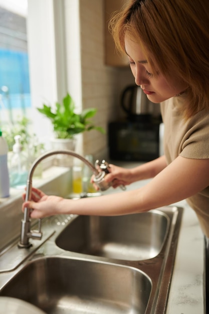 Femme changeant le robinet d'évier qui fuit