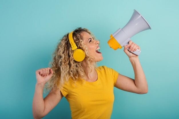 Une femme chante avec un haut-parleur et écoute de la musique avec une expression joyeuse du casque