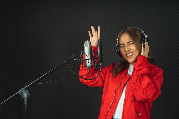 Femme chanteuse asiatique dans un studio d'enregistrement utilisant un microphone de studio avec passion dans un studio d'enregistrement musical