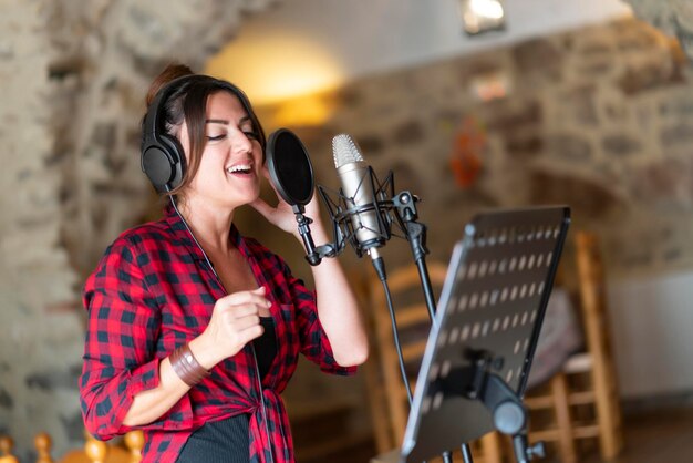 Femme chanteuse professionnelle enregistrant une chanson à la maison