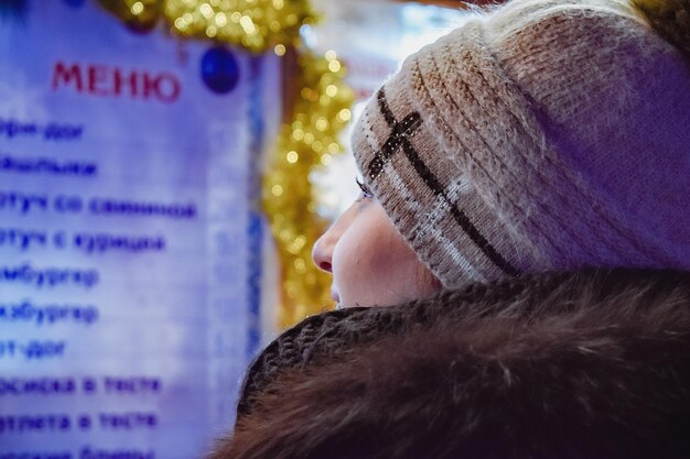 Une femme avec un chapeau blanc regarde un menu dans une vitrine.