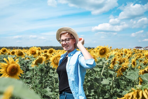 Femme avec chapeau dans le champ de tournesols profitant de la nature