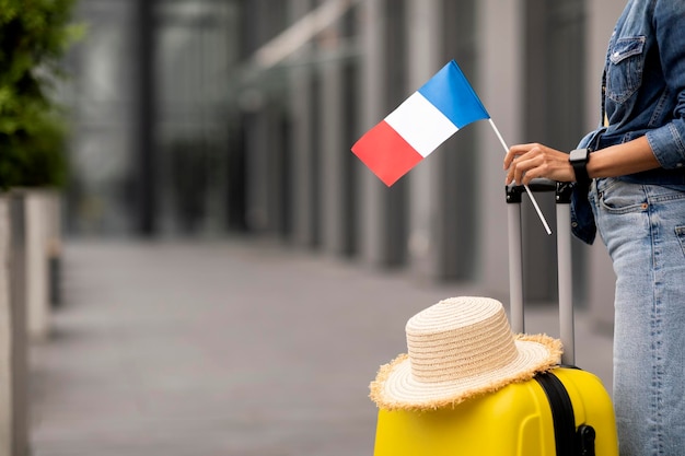 Femme avec chapeau de paille sur les bagages tenant le drapeau de la France