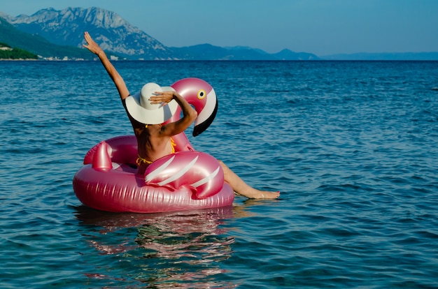 Femme avec un chapeau de paille blanc sur Flamingo floatie.