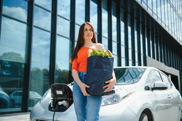 La femme charge la voiture électrique de location