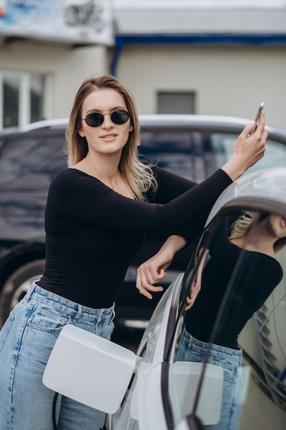 Femme chargeant une voiture électrique à la station d&#39;essence électrique