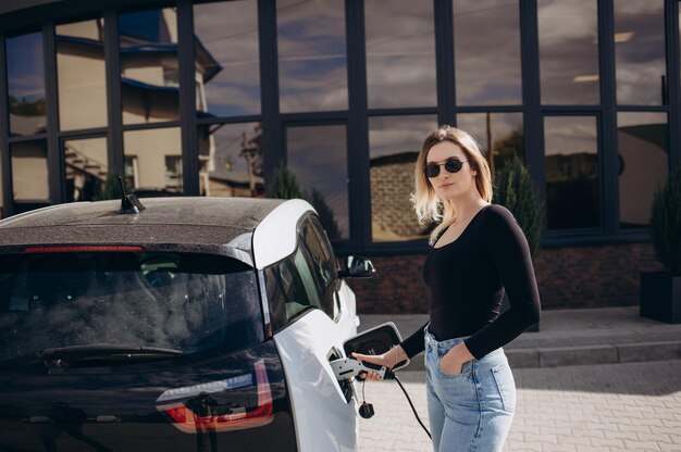 Femme chargeant une voiture électrique à la station d&#39;essence électrique