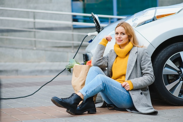 Femme chargeant une voiture électrique à la station-service électrique