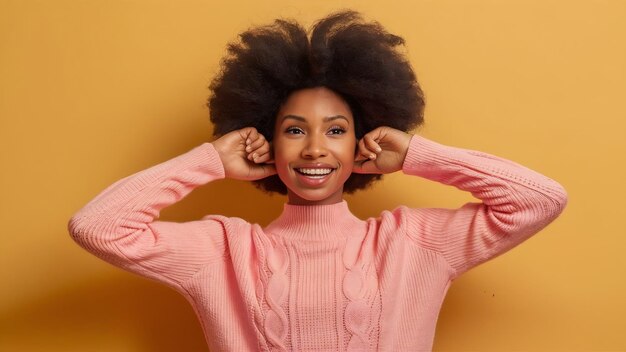 Une femme charmante avec un afro posant dans un pull rose