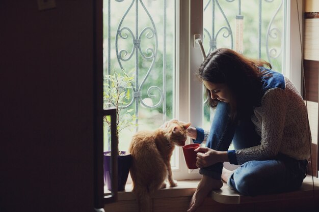 Femme avec un chat dans une fenêtre