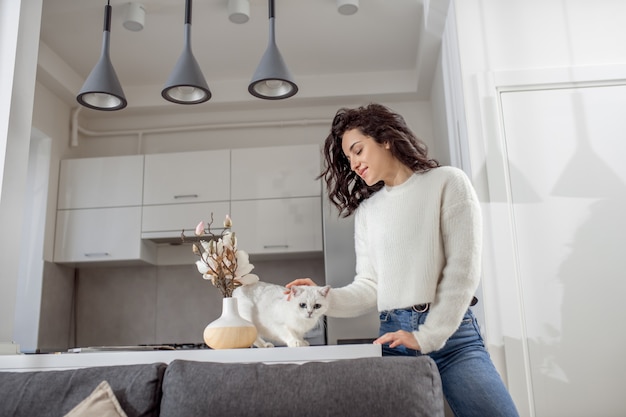 Une femme avec un chat. Jeune femme aux cheveux noirs et son ami blanc moelleux