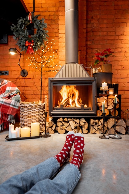 Femme en chaussettes de Noël au coin du feu à la maison. Le concept de confort pendant les vacances d'hiver et du Nouvel An