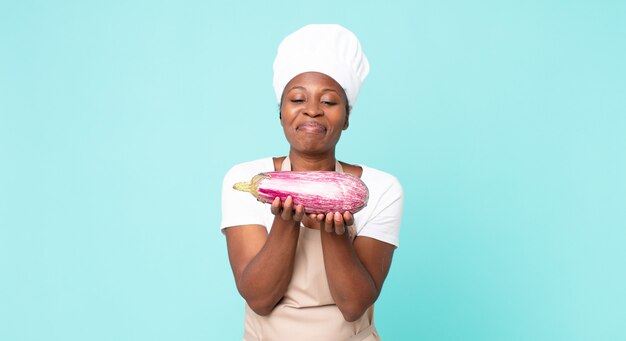 Femme de chef adulte afro-américaine noire tenant une aubergine