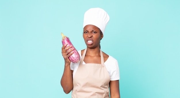 Femme de chef adulte afro-américaine noire tenant une aubergine
