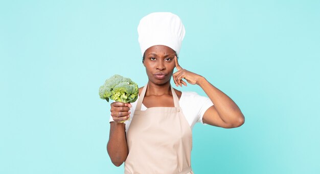 Femme de chef adulte afro-américaine noire tenant un brocoli