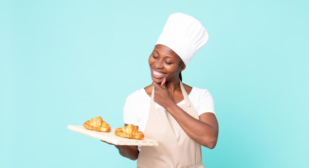 Femme chef adulte afro-américaine noire tenant un plateau de croissants