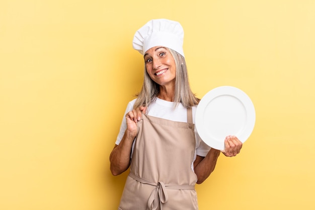 Femme chef d'âge moyen à l'air arrogante, réussie, positive et fière, pointant vers soi et tenant un plat