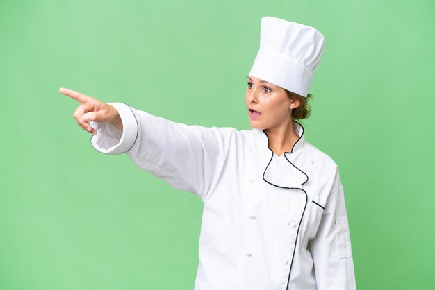 Femme chef d'âge moyen sur fond isolé pointant vers l'extérieur