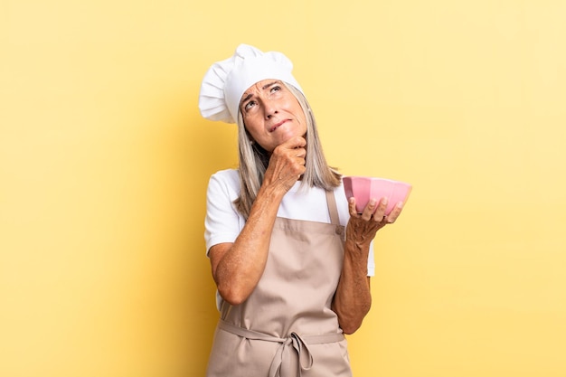 Femme chef d'âge moyen pensant, se sentant dubitative et confuse, avec différentes options, se demandant quelle décision prendre et tenant un pot vide