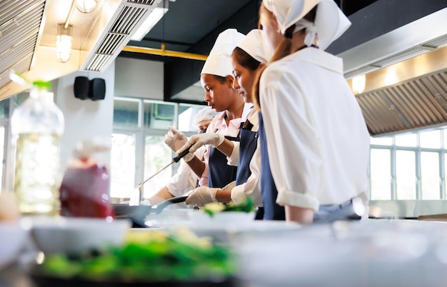 Une femme chef asiatique senior enseigne à un étudiant Cours de cuisine un groupe de classe culinaire de jeunes étudiantes multiethniques heureuses se concentre sur des cours de cuisine dans une école de cuisine