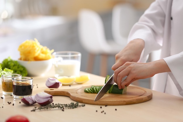 Photo femme chef cuisinant des aliments à la table de cuisine agrandi