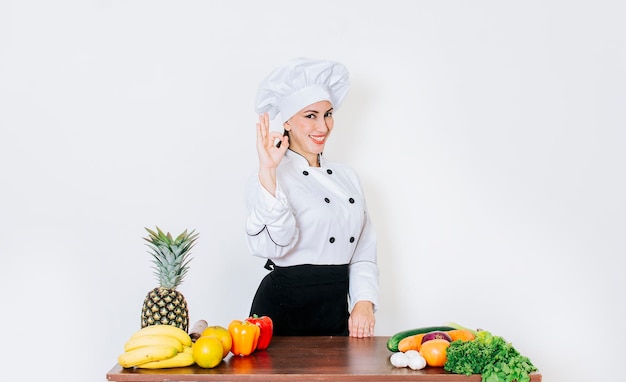 Femme chef faisant un geste ok une femme chef à une table de légumes avec le pouce levé Concept d'une femme chef recommandant des légumes frais