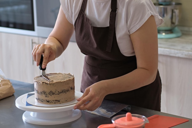 Femme chef pâtissier lignes crème au chocolat sur gros plan de gâteau au chocolat Processus de fabrication de gâteaux Mise au point sélective