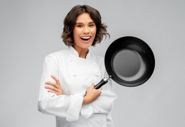 Photo une femme chef souriante dans un toque avec une poêle à frire