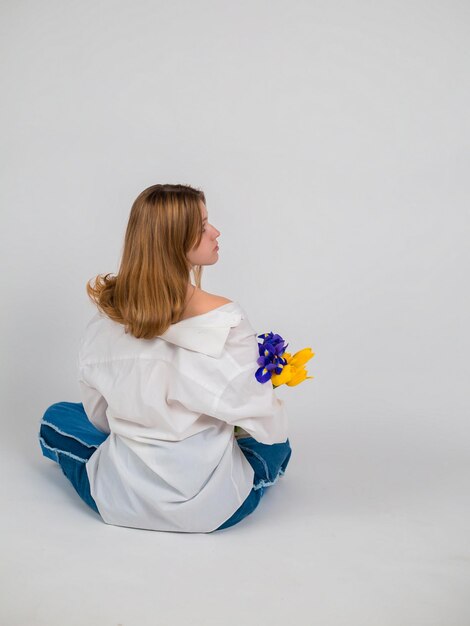 Une femme en chemise blanche et blubouquet de tulipes et iris fête des femmes fête des mères Da